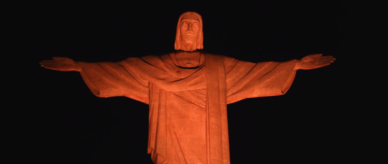 A foto mostra Cristo Redendor iluminado com a cor laranja