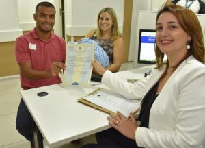 Os pais do primeiro recém-nascido a obter a certidão de nascimento com CPF exibem o documento satisfeitos com o serviço (Foto: ARPEN-RJ)